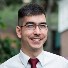 Photo of Frank wearing a white button down shirt and red tie