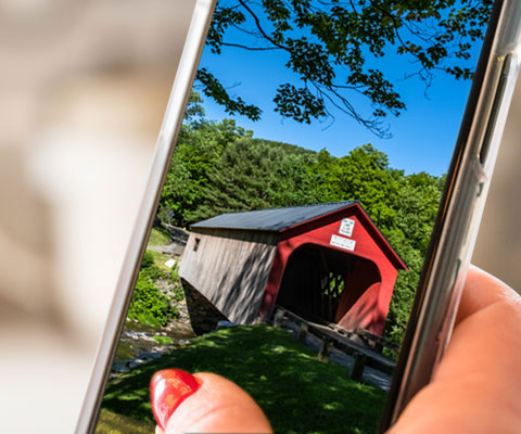 Close up photo of smartphone photo of red covered bridge on phone screen