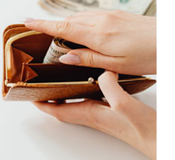 close up photo of a woman's hands opening a brown leather wallet with money inside
